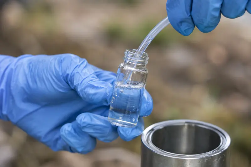 Groundwater sampling into glass vial with blue gloves